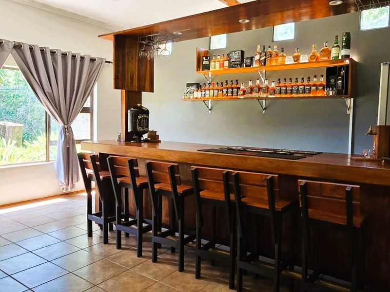 A well-appointed home bar area featuring a custom wooden counter, integrated shelving, and tiled flooring, creating an ideal space for entertaining.