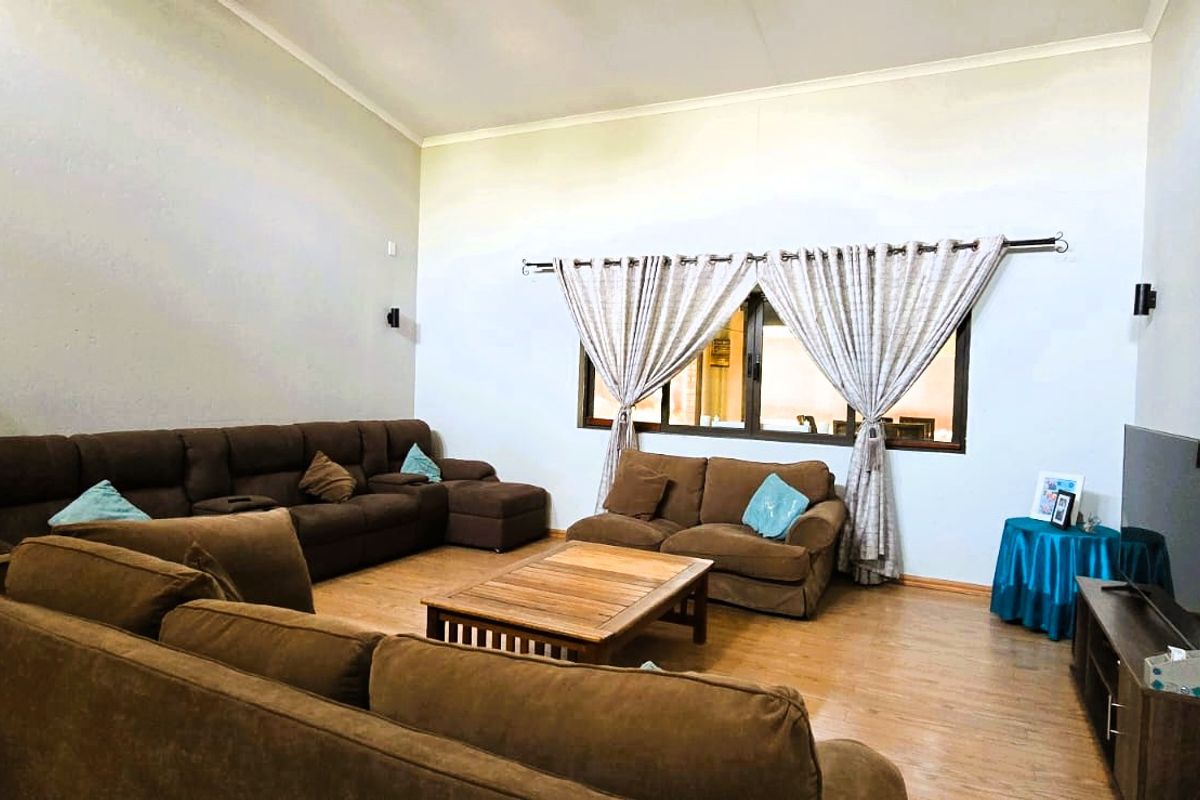Spacious living room featuring high vaulted ceilings, laminate flooring, and a large window allowing natural light into the area.