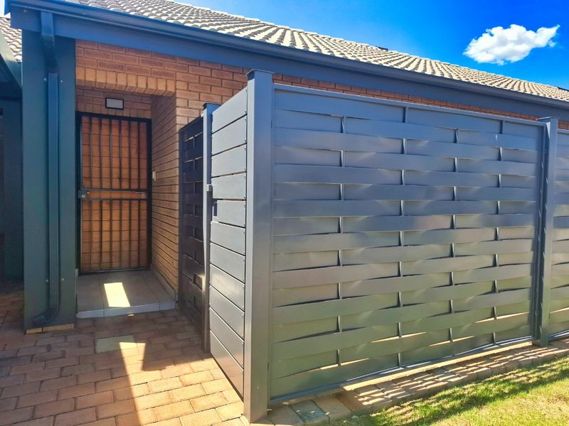 A well-maintained front entrance featuring a brick facade, tiled roof, and a modern privacy screen, providing a secure and tidy approach to the home.