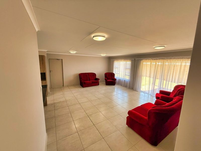 Spacious living area featuring neutral tiled flooring, flush mount lighting, and large sliding glass doors providing ample natural light.