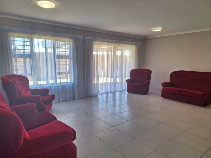 Spacious living room featuring neutral tiled flooring, large windows, and sliding glass doors that provide ample natural light.