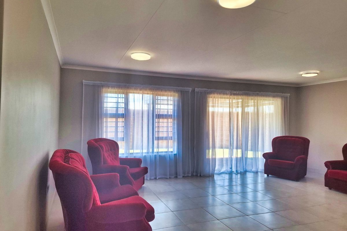 Spacious living room featuring neutral tiled flooring, flush mount ceiling lights, and large windows with security bars and sliding door access to the exterior.