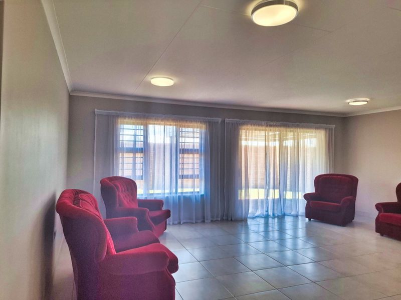 Spacious living room featuring neutral tiled flooring, flush mount ceiling lights, and large windows with security bars and sliding door access to the exterior.
