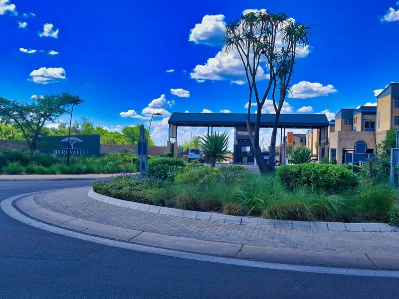 The entrance to Bergvallei estate features a well-maintained security gatehouse, landscaped roundabout, and paved driveway, providing a secure and welcoming arrival.