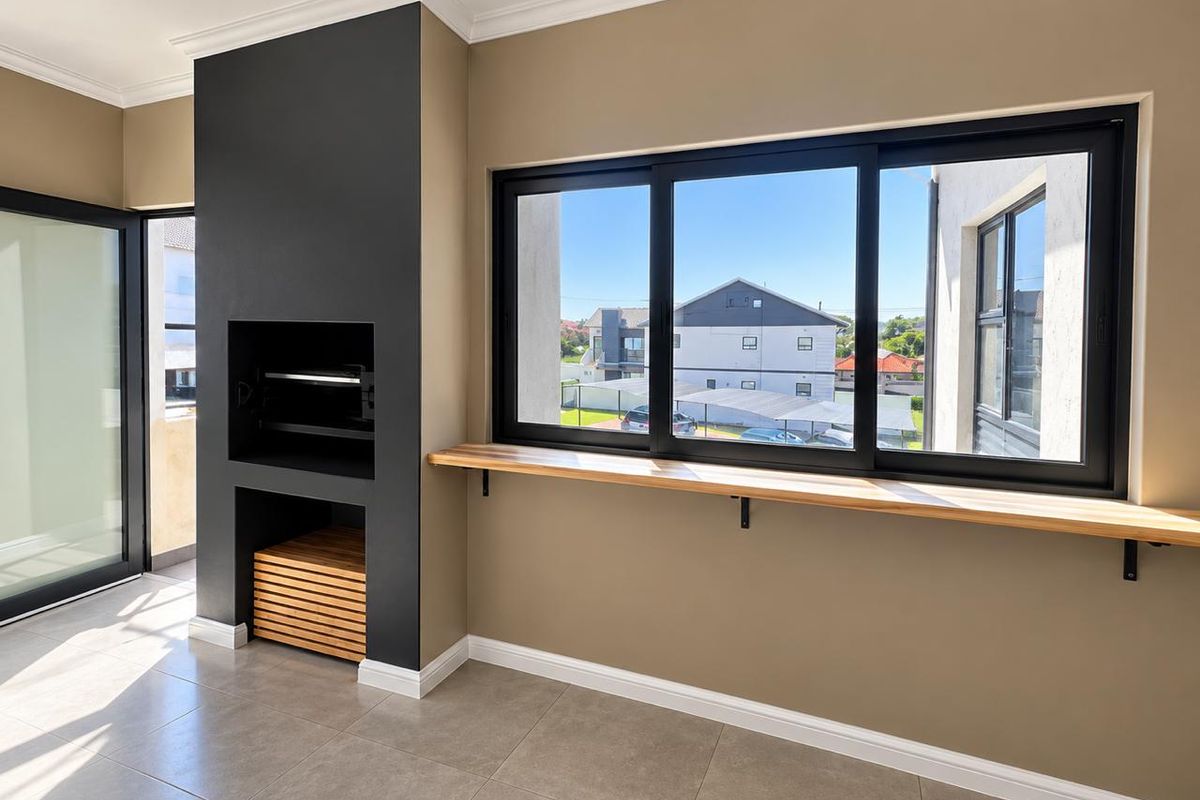 Modern living area featuring a built-in braai, sleek tiled flooring, and large sliding windows with a timber sill, offering a bright and contemporary space.