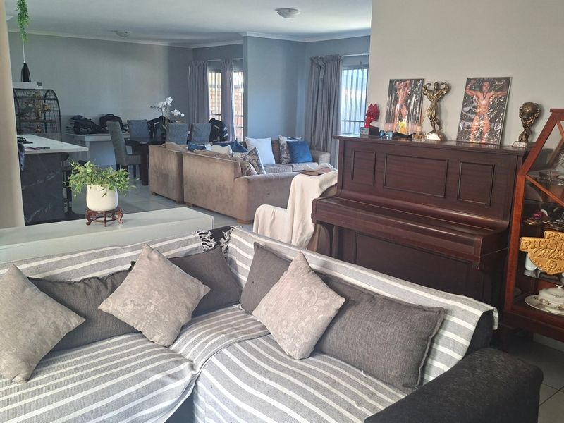 Spacious open-plan living area featuring tiled flooring and neutral wall tones, seamlessly connecting the lounge and dining spaces for a comfortable family environment.