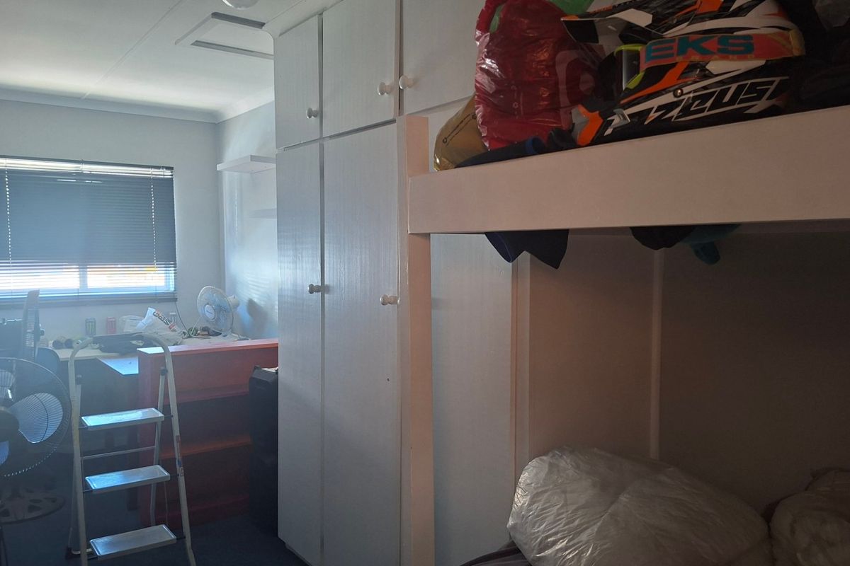 A bedroom featuring built-in cupboards and a window with fitted blinds, offering functional storage space.