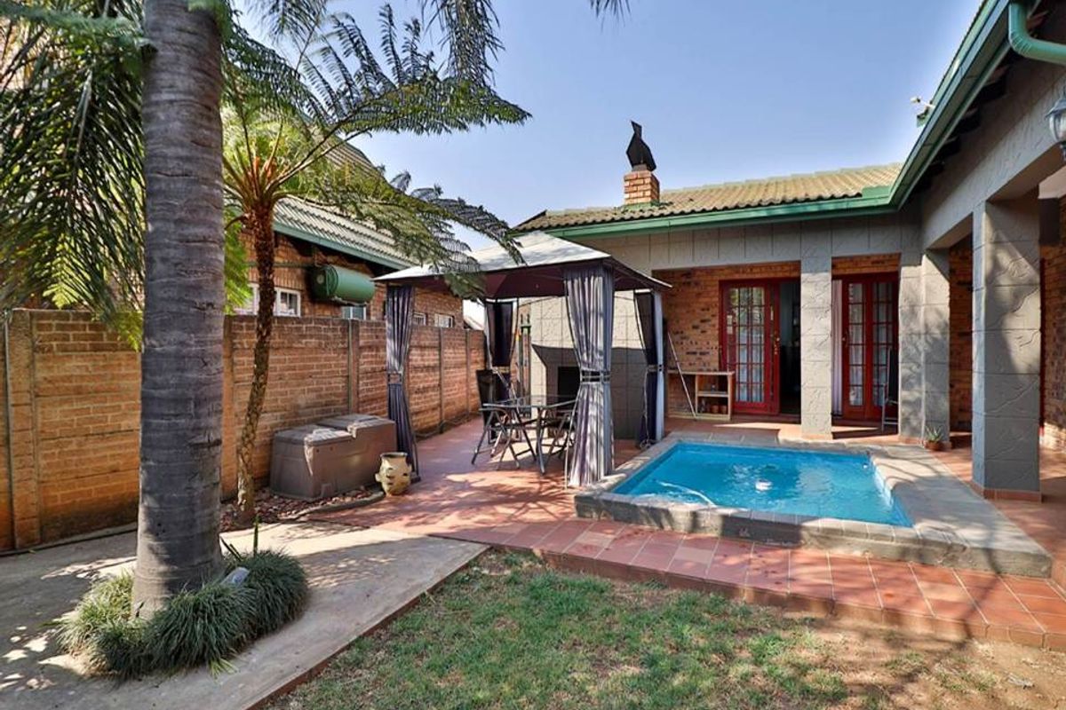 Rear exterior view featuring a small swimming pool, tiled patio area, and brick boundary walls in a private garden setting.