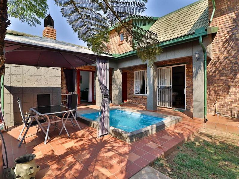 A private rear courtyard featuring a compact swimming pool, tiled patio area, and an integrated outdoor brick fireplace, perfect for entertaining.
