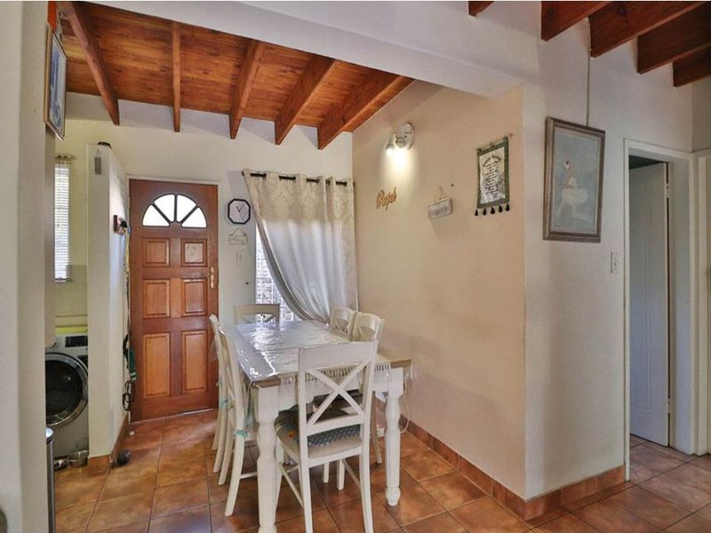 Dining area featuring exposed timber ceiling beams, ceramic floor tiles, and a traditional timber front door, creating a warm and rustic atmosphere.
