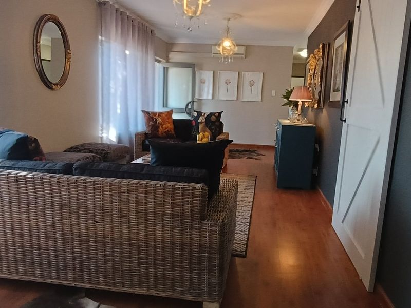 A well-maintained living room featuring laminate flooring, a sliding barn door, and a split-system air conditioner, creating a comfortable and functional living space.