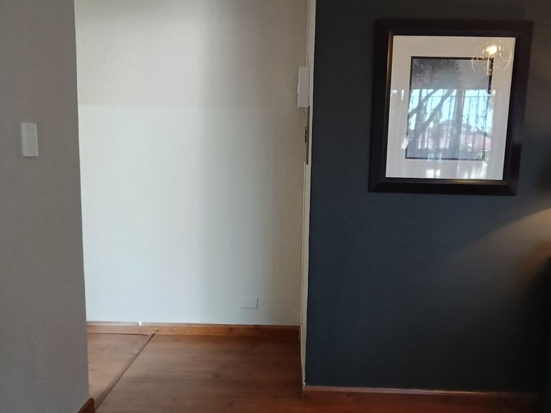 A clean hallway space featuring timber flooring and contrasting wall finishes, providing a neutral transition area within the home.