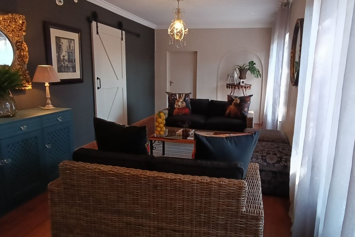 A well-maintained living room featuring a distinctive barn-style sliding door, an arched wall niche, and warm hardwood flooring.