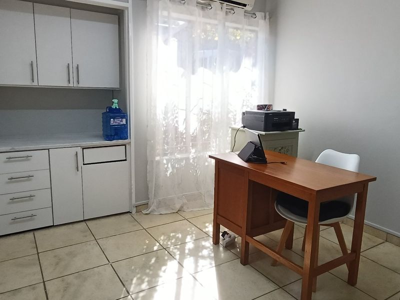 A functional home office space featuring built-in cabinetry, tiled flooring, and an integrated air conditioning unit, offering a practical workspace.