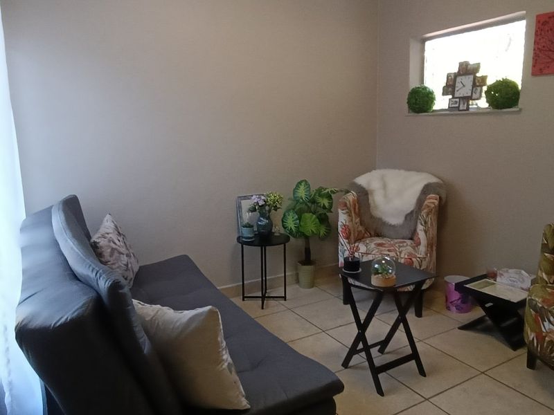 A compact living area featuring neutral wall tones, tiled flooring, and a horizontal window providing natural light.