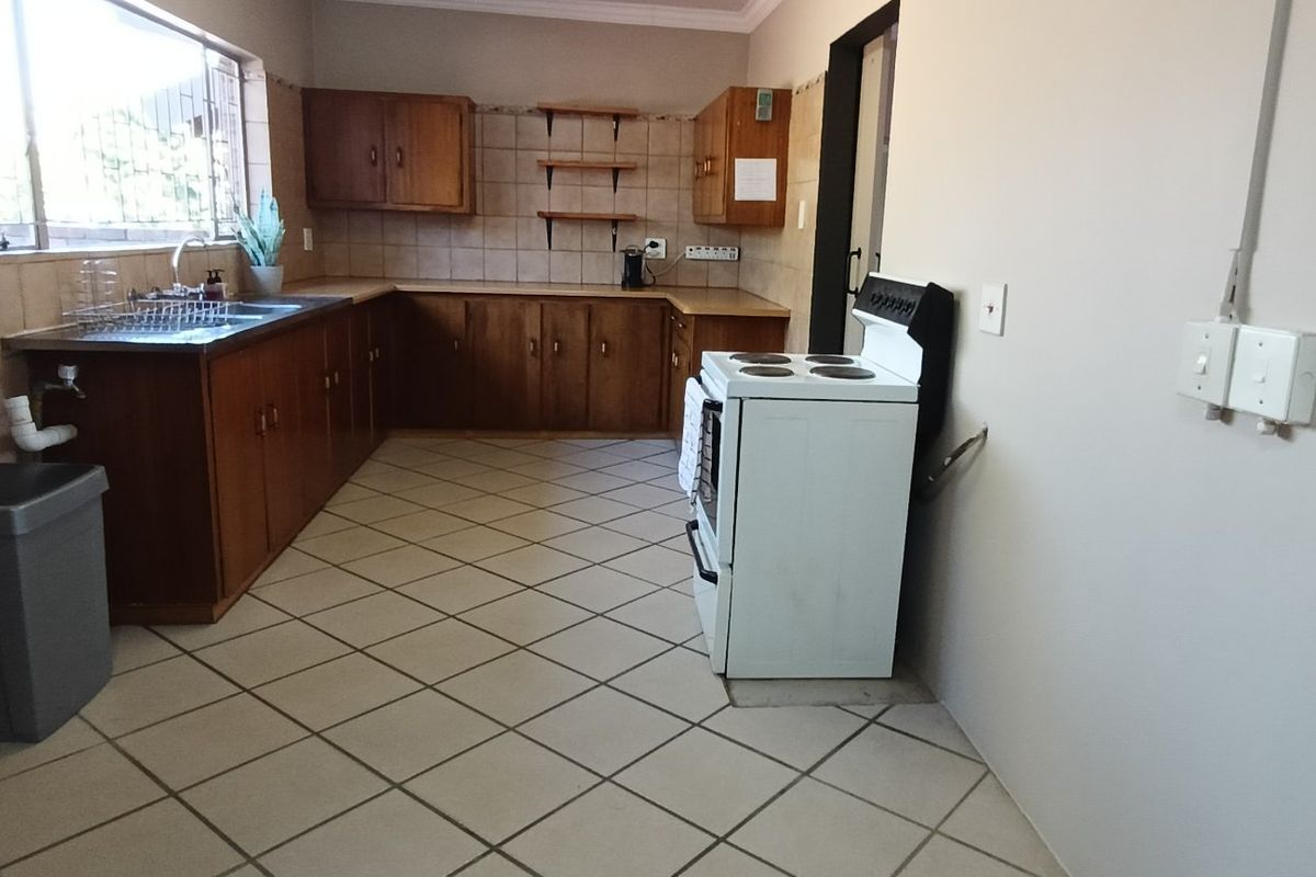 A functional kitchen featuring wooden cabinetry, tiled splashbacks, and ceramic flooring, offering a practical layout with potential for modern cosmetic updates.