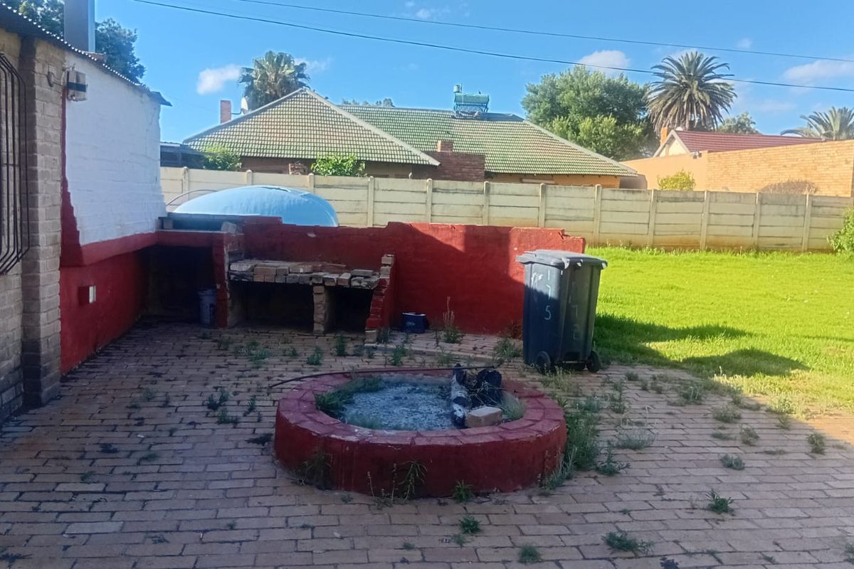 Rear garden area featuring a brick-paved patio, a built-in brick braai, and a circular fire pit, set within a fenced backyard.