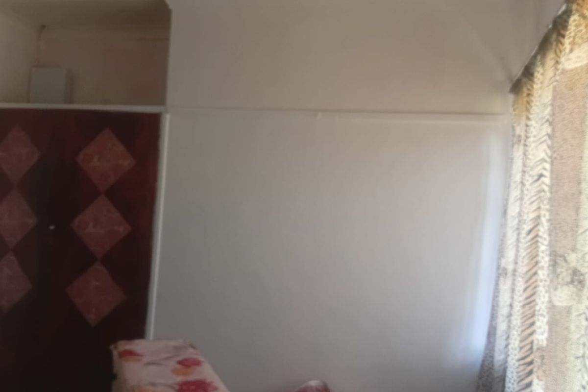 A bedroom featuring a built-in wardrobe with a dated finish, requiring cosmetic updates to modernize the space.