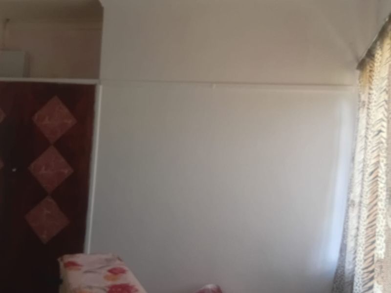 A bedroom featuring a built-in wardrobe with a dated finish, requiring cosmetic updates to modernize the space.