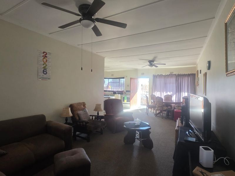 An open-plan living and dining area featuring ceiling fans and direct access to an outdoor space through a sliding door.