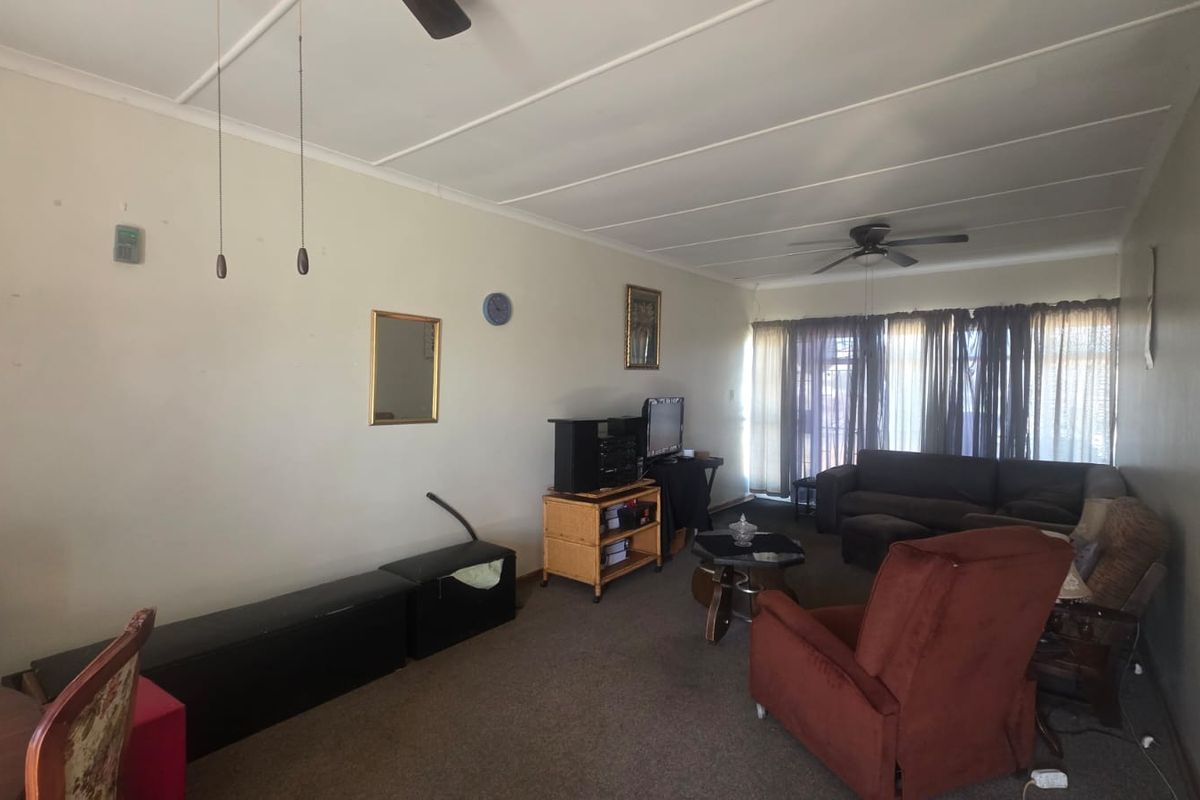 Spacious living room featuring a ceiling fan and large sliding glass doors that provide natural light, offering a blank canvas for renovation.
