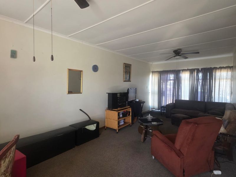 Spacious living room featuring a ceiling fan and large sliding glass doors that provide natural light, offering a blank canvas for renovation.