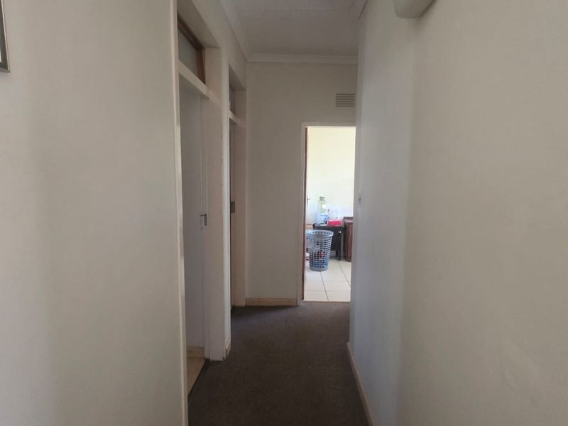 A functional interior hallway featuring carpeted flooring and access to multiple rooms within the apartment.