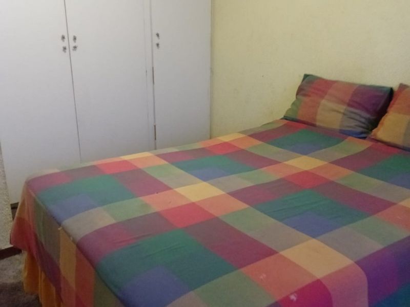 A bedroom featuring built-in cupboards and carpeted flooring, requiring cosmetic updates to the wall finishes.