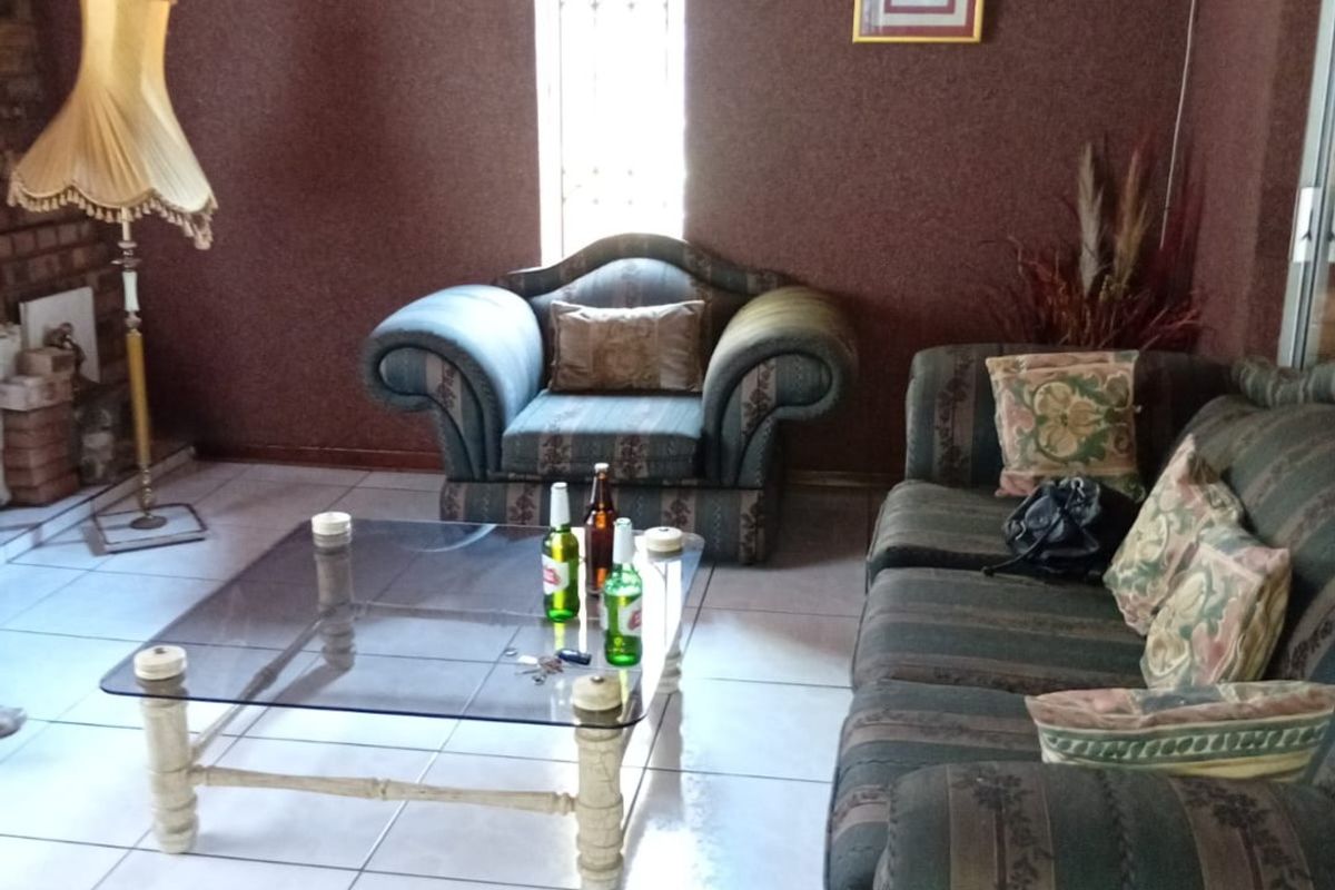 A living room featuring tiled flooring and a timber ceiling, with a narrow window fitted with security bars.