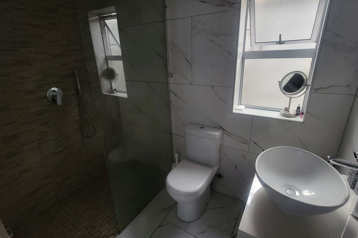 Modern bathroom featuring a walk-in shower with glass screen, vessel sink vanity, and contemporary marble-look wall tiling.
