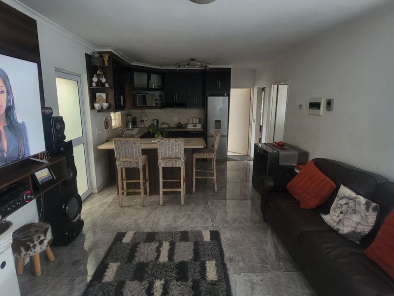 Open-plan living and kitchen area featuring tiled flooring, a central kitchen island with breakfast bar seating, and modern cabinetry.