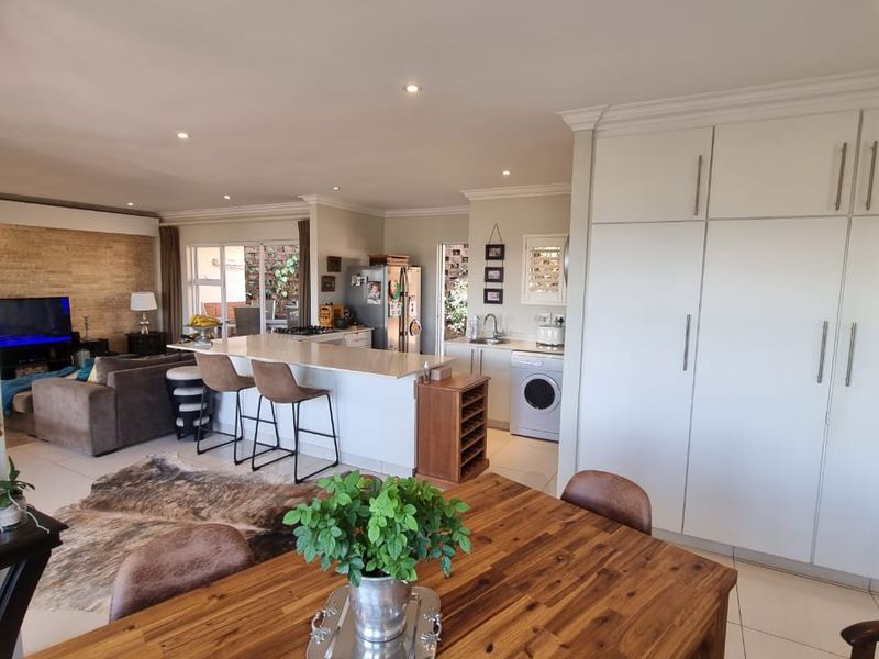 Spacious open-plan living area featuring a modern kitchen with stone countertops, ample built-in cabinetry, and seamless flow to the dining and lounge spaces.
