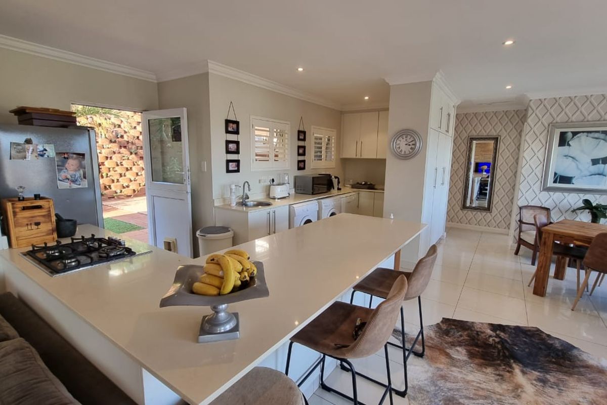 Spacious open-plan kitchen and dining area featuring a large central island with gas hob, modern cabinetry, and seamless flow to the outdoor patio.