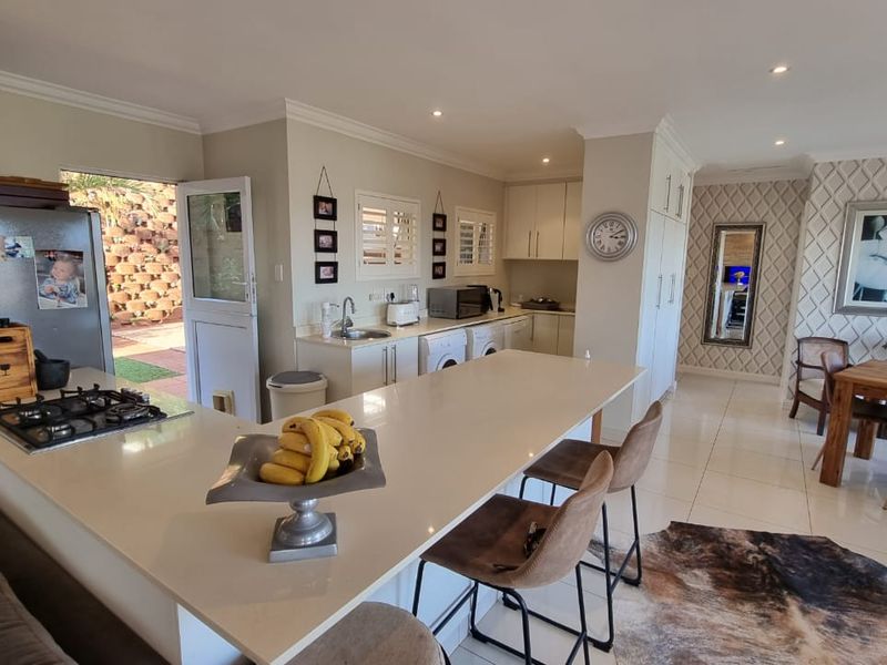 Spacious open-plan kitchen and dining area featuring a large central island with gas hob, modern cabinetry, and seamless flow to the outdoor patio.