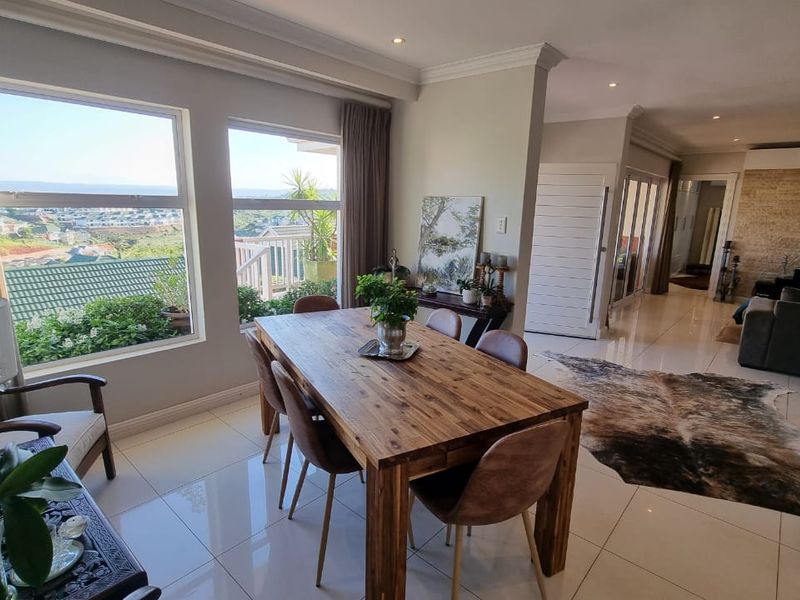 Spacious open-plan living and dining area featuring polished porcelain tiles, recessed lighting, and large windows offering expansive views.
