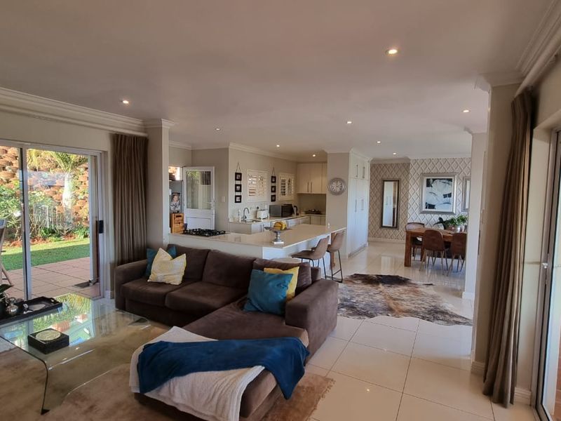 Spacious open-plan living area featuring a modern kitchen with island, tiled floors, and large sliding doors opening to a private patio.