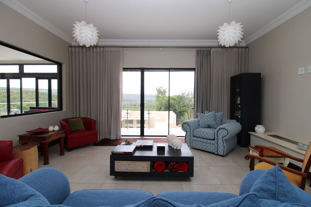 Spacious living room featuring large sliding glass doors that open to an outdoor patio, complemented by neutral tiled flooring and elegant ceiling molding.