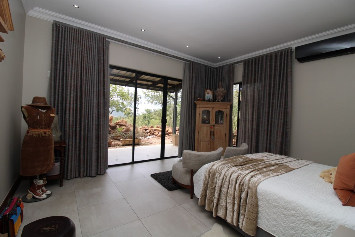 Spacious bedroom featuring large sliding glass doors that open to an outdoor patio, tiled flooring, recessed lighting, and a wall-mounted air conditioning unit.