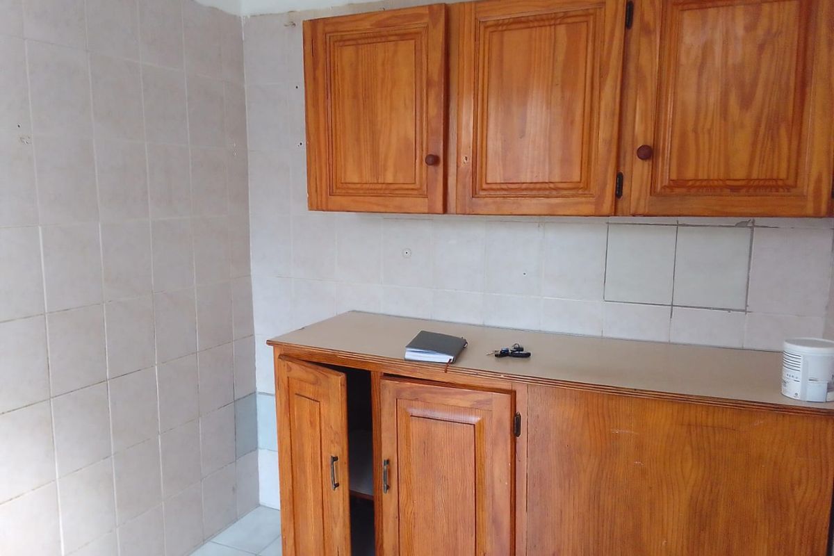 A dated kitchen area featuring wooden cabinetry, tiled splashbacks, and tiled flooring, offering a blank canvas for potential modernization and renovation.