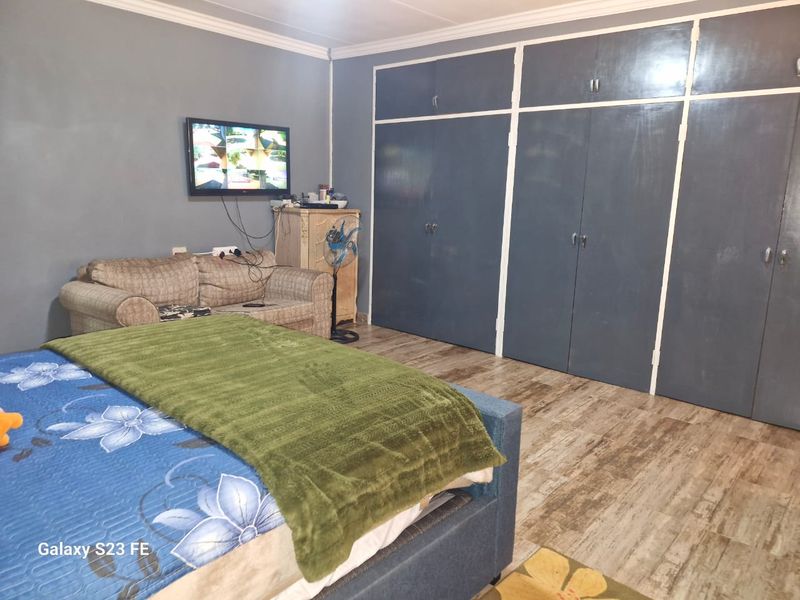 A bedroom featuring built-in cupboards, laminate flooring, and coved ceiling details.