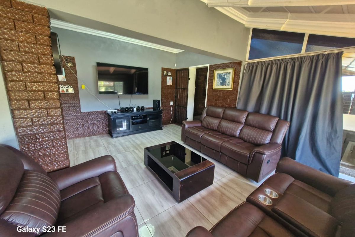 A living room featuring an exposed brick accent wall, tiled flooring, and coved ceiling details.