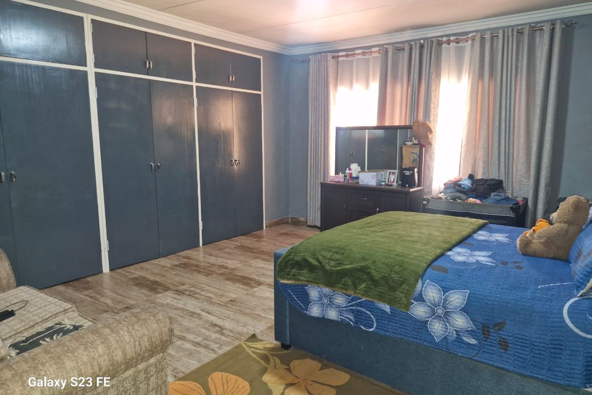 Spacious bedroom featuring extensive built-in cupboards, modern laminate flooring, and decorative ceiling cornicing, offering a functional and comfortable living space.