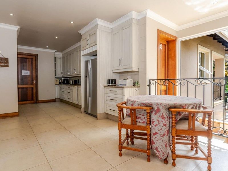 A well-maintained kitchen featuring classic cabinetry, tiled flooring, and recessed lighting, with an open transition to an adjacent balcony area.