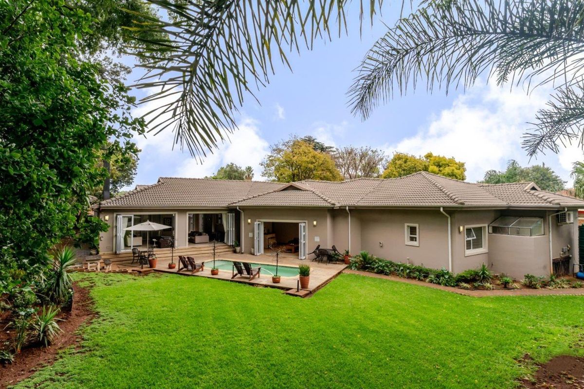 Spacious rear exterior featuring a well-maintained garden, swimming pool, and paved patio area with seamless access to the home through bi-fold doors.