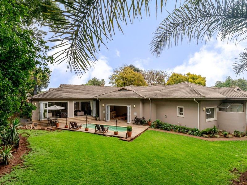 Spacious rear exterior featuring a well-maintained garden, swimming pool, and paved patio area with seamless access to the home through bi-fold doors.