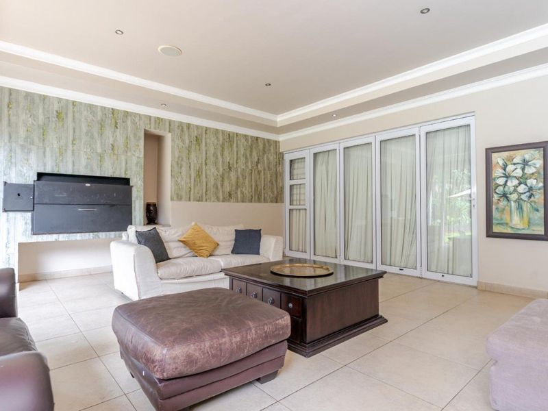 Spacious living room featuring tiled floors, a built-in fireplace with decorative wall paneling, and large sliding glass doors providing access to the outdoors.