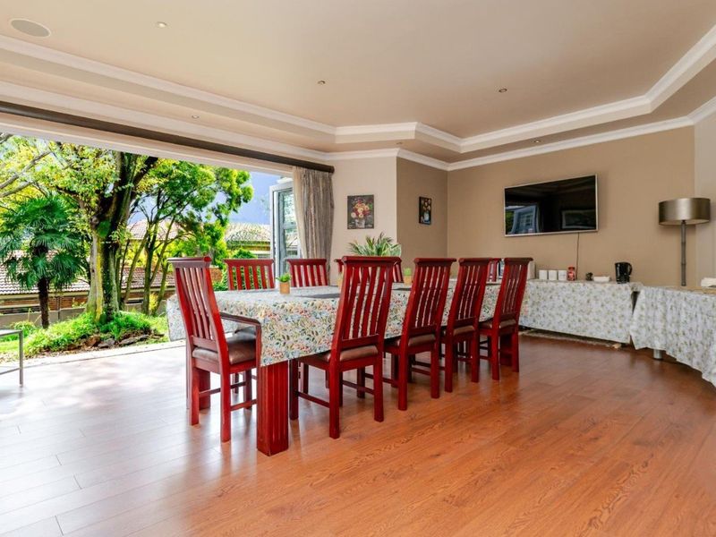 Spacious dining room featuring laminate flooring, recessed ceiling lighting, and large sliding glass doors that open to a lush garden view.