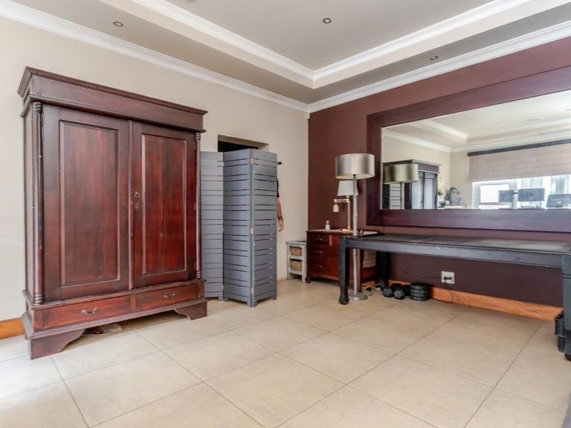Spacious living area featuring neutral tiled flooring, recessed ceiling lighting, decorative crown molding, and a large built-in wall mirror.