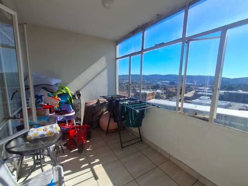 Enclosed balcony featuring tiled flooring and expansive glass windows offering elevated urban views, providing a versatile space for relaxation or utility use.