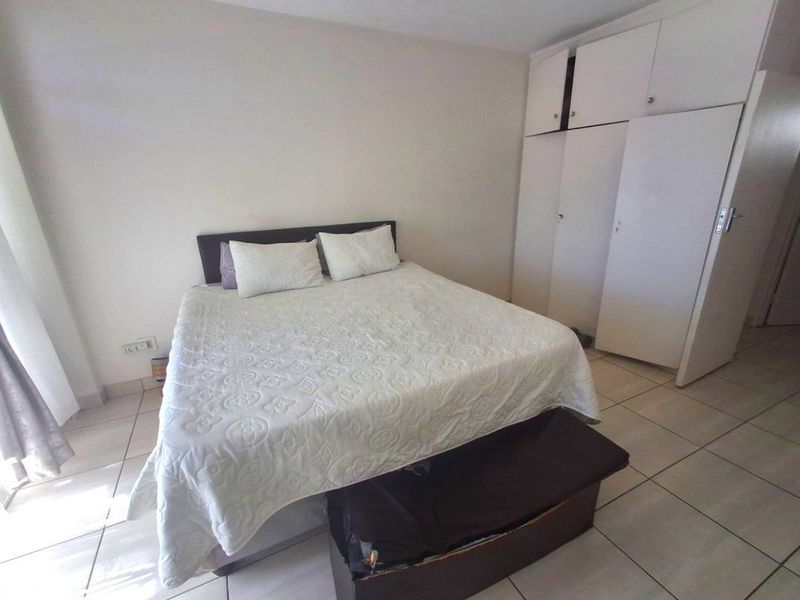 A bedroom featuring tiled flooring and built-in cupboards, providing functional storage space.
